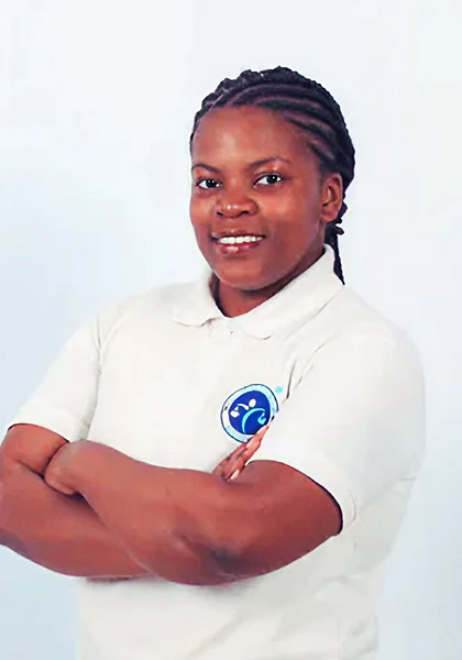 Confident woman with braided hair, arms crossed, wearing a branded polo shirt, smiling against a white background.