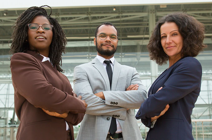 Confident diverse business team. Three professionals in suits stand with arms crossed. Leadership, teamwork and success concept.