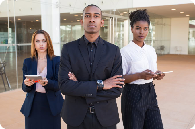 Confident diverse business team: African American man in suit with two women holding tablets, leadership and teamwork concept.