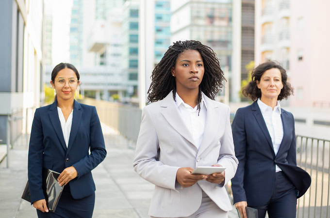 Three confident businesswomen walking in suits. Diverse professional women team, leadership concept. Business and success.