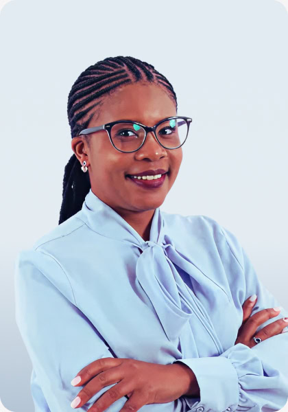 Woman smiles with arms crossed, wearing glasses and a light blue blouse with a bow.